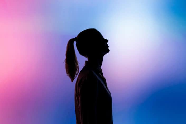  silueta de una mujer mirando hacia arriba sobre un fondo azul y rosa