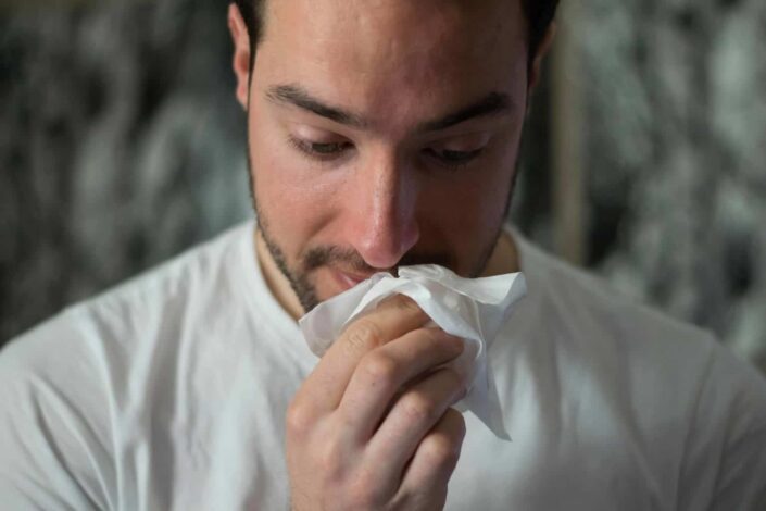 hombre limpiándose la nariz con papel de seda