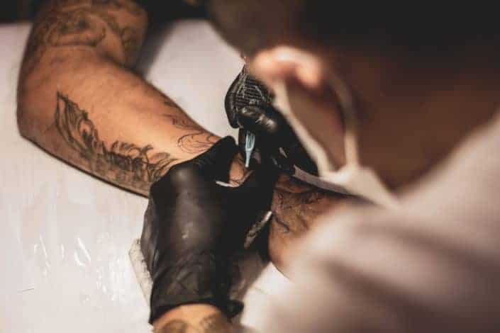 hombre tatuando el brazo derecho de la persona