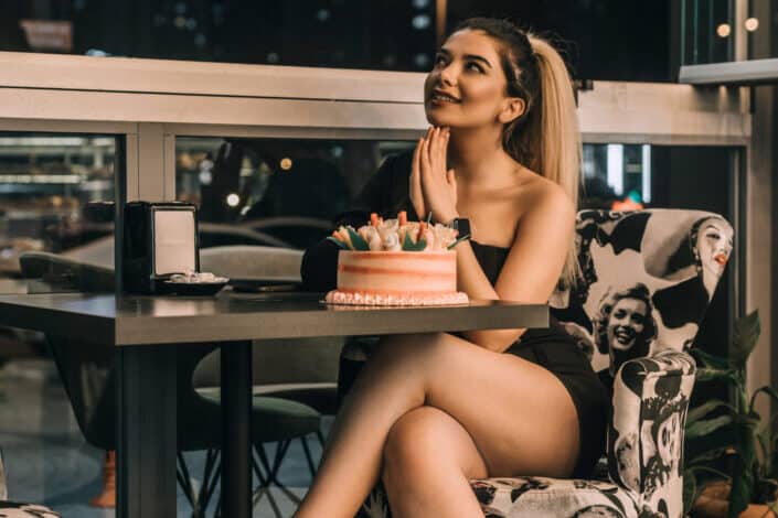 dama haciendo un deseo de cumpleaños frente a su pastel