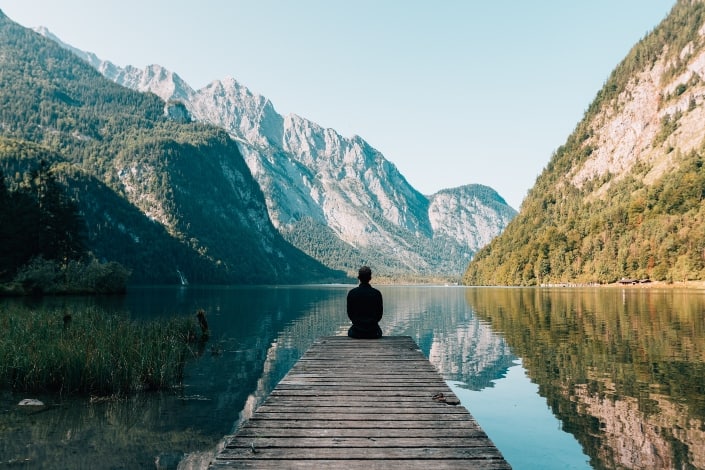 hombre sentado junto al lago disfrutando de su vista