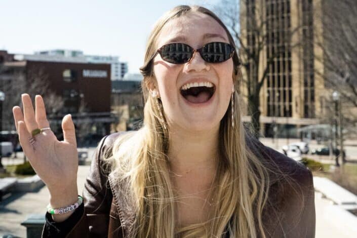  Chica sonriente con gafas de sol de pie en Madison, Wisconsin.