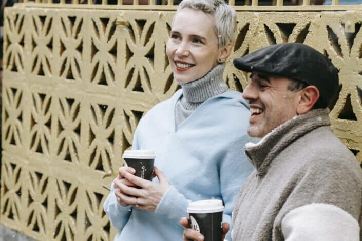Hombre y mujer charlando mientras bebe café afuera en un clima frío