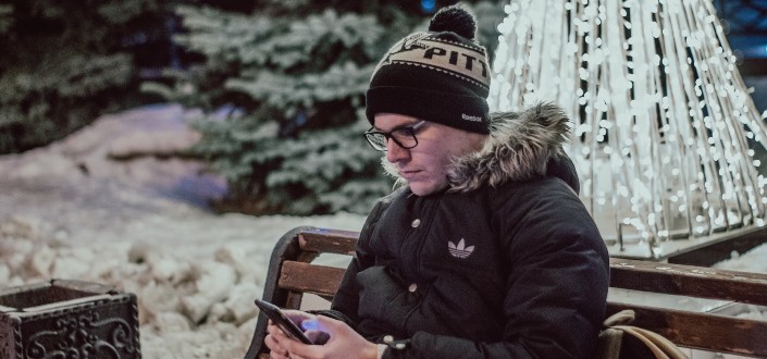 Hombre frío con smartphone en un banco