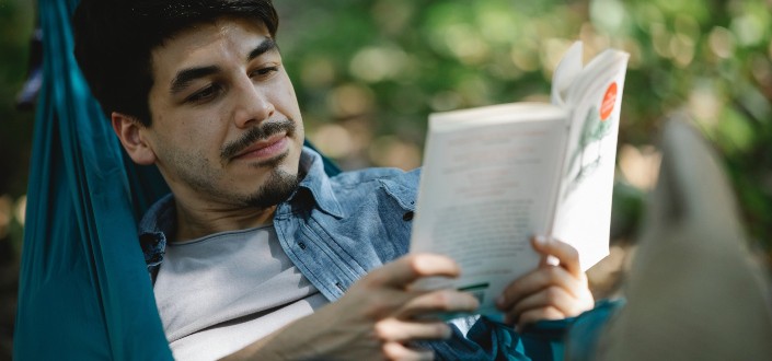 Hombre barbudo concentrado con libro en hamaca