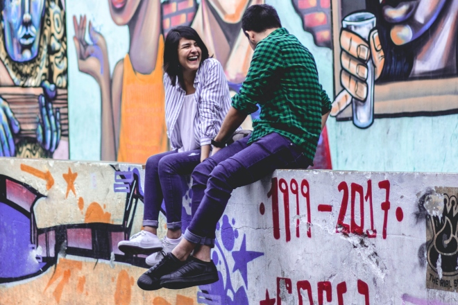 Cumplidos divertidos - hombre y mujer sentados cerca de la pared mientras se ríen entre ellos
