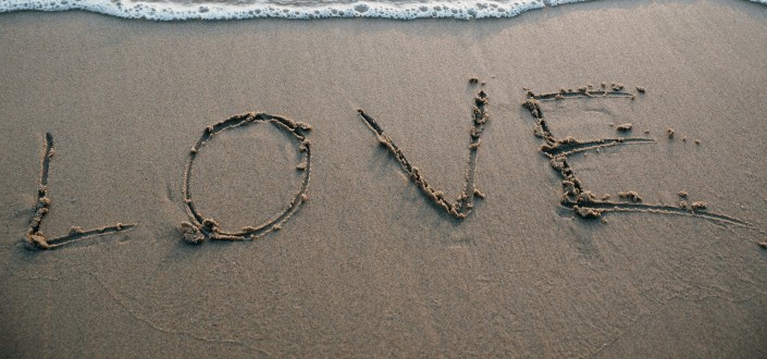 Love text from brown sand on the sea shore