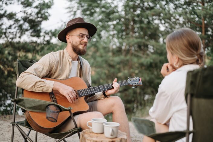 a-bearded-man-playing-guitar-while-looking-at-the-woman-sitting-in-front-of-him-