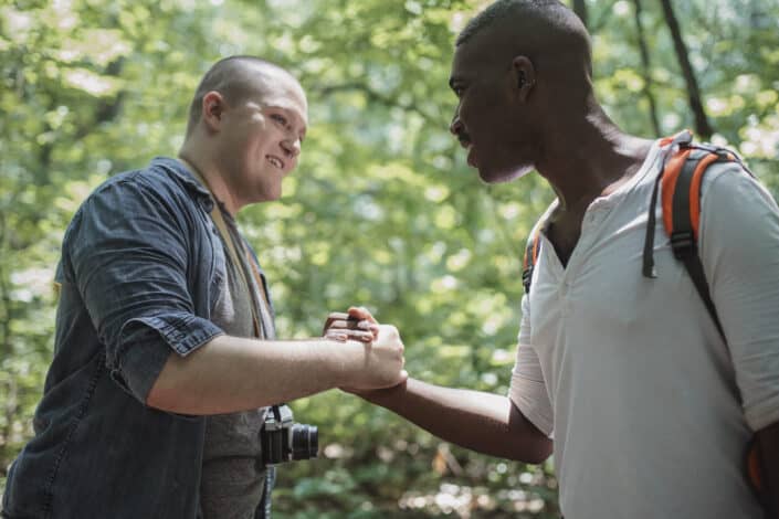 Hombres multiétnicos positivos estrechando la mano en el bosque